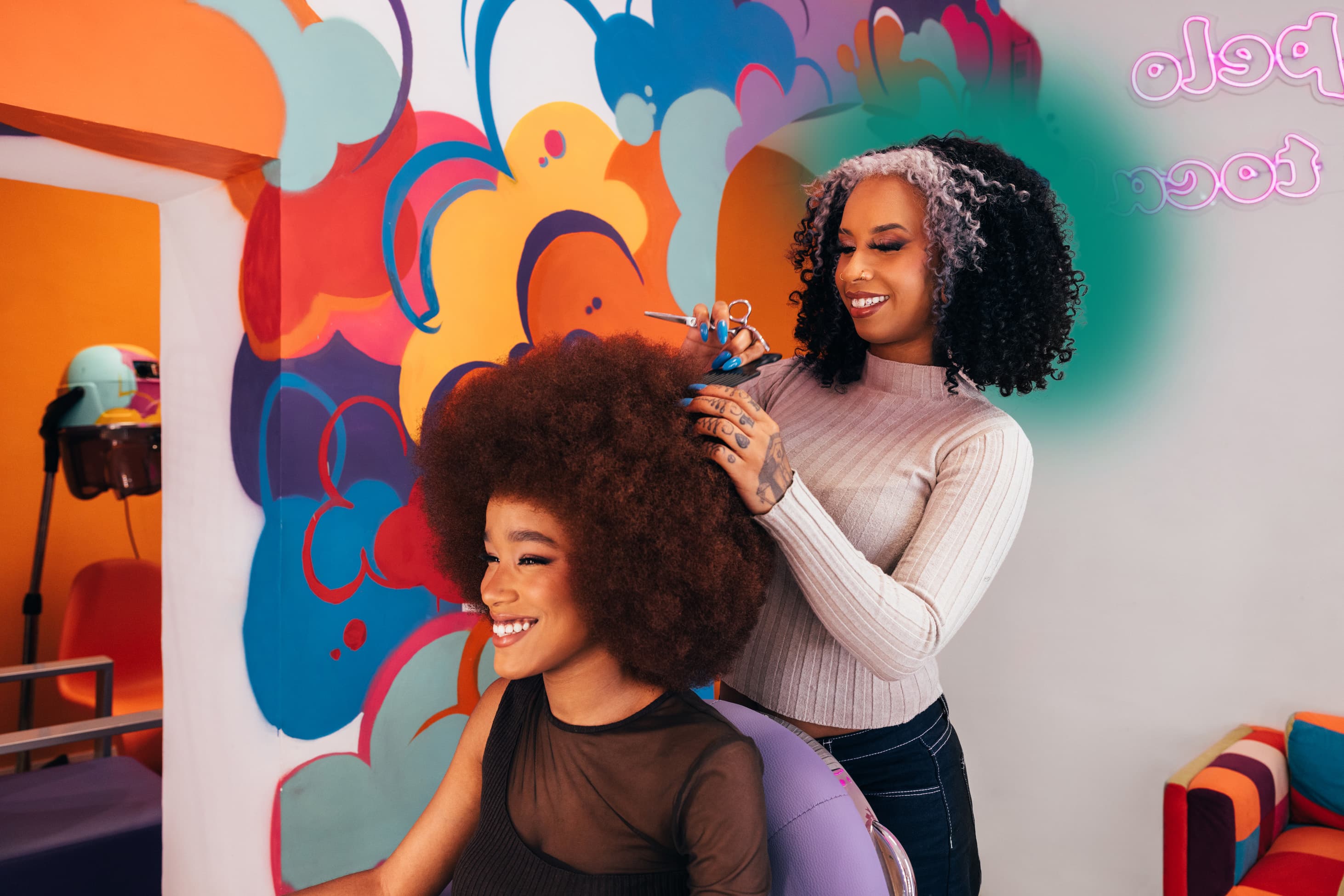 A stylist cutting a client's Afro in a colourful salon